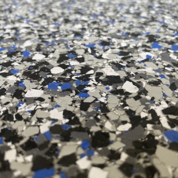 Close-up of a speckled surface with black, white, and blue flakes, possibly a flooring material or a countertop with a terrazzo-like appearance.