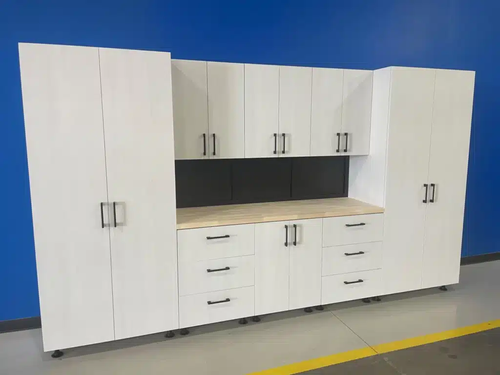 A large white storage cabinet with shelves, drawers, and a black countertop, against a blue wall on a gray floor with yellow lines.