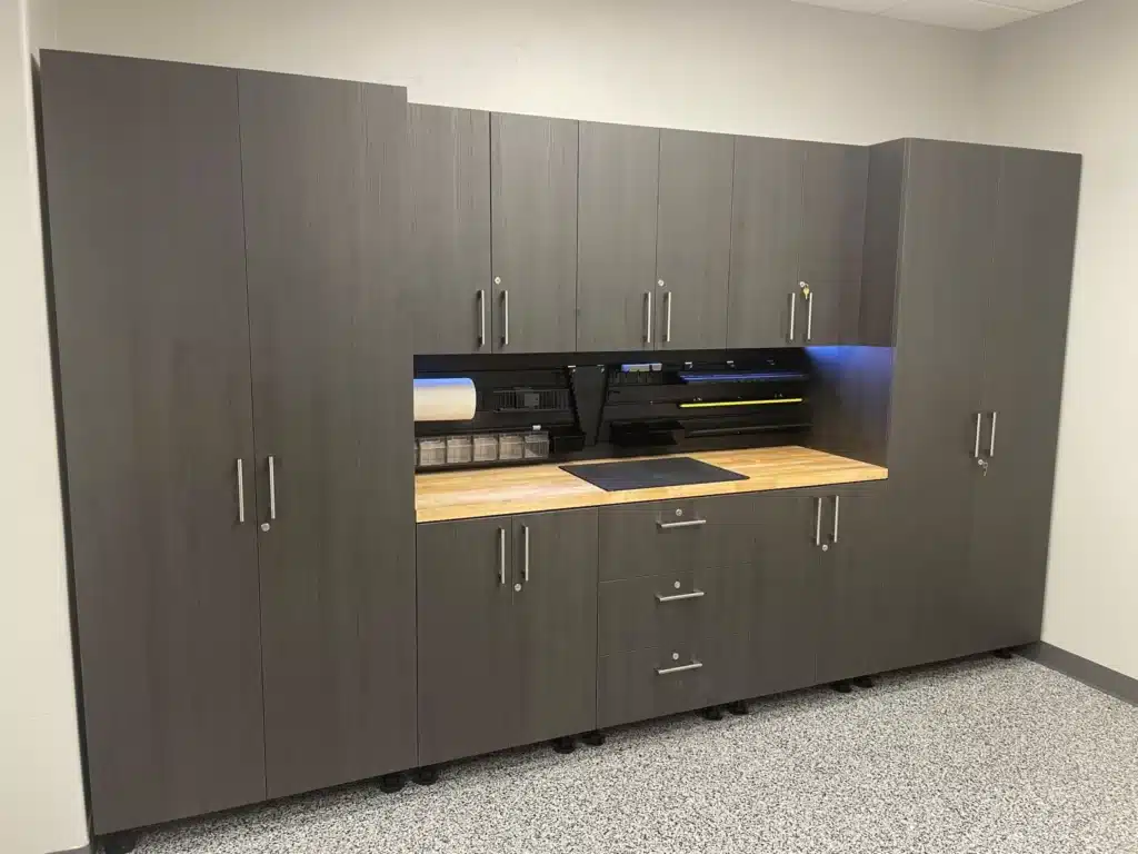 A dark wood office cabinet with a built-in multifunction printer. The cabinet has shelving, drawers, and under-cabinet lighting on a speckled floor.