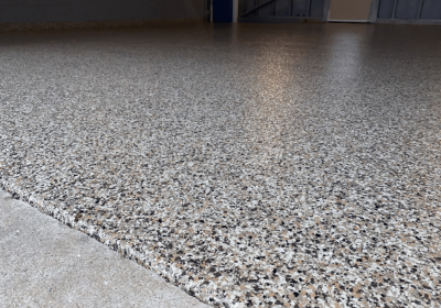 This image shows a close-up of a speckled floor with a smooth and reflective surface transitioning to a rougher textured area, likely in an indoor space.